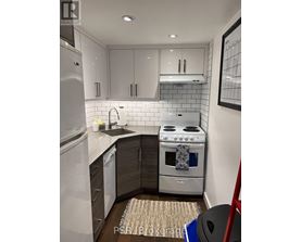 A modern kitchen with a stove, sink, and refrigerator.