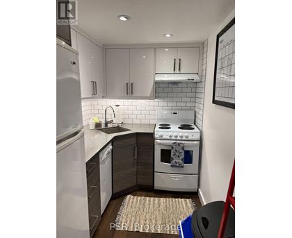 A modern kitchen with a stove, sink, and refrigerator.