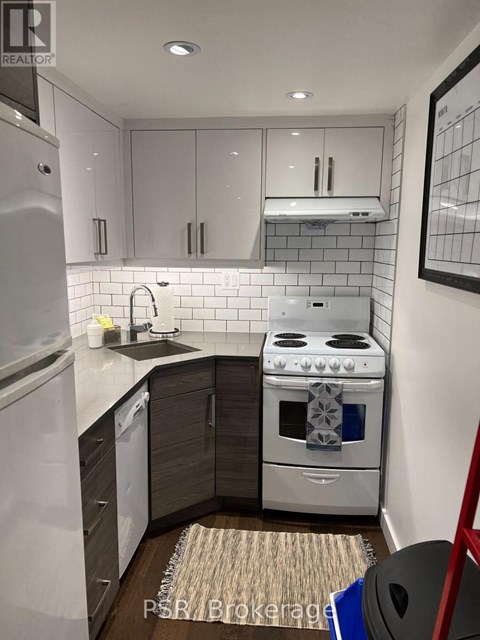 A modern kitchen with a stove, sink, and refrigerator.