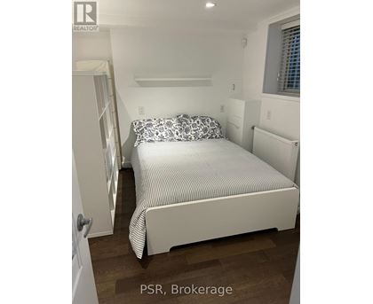 A bedroom with a bed, pillows, and a window.