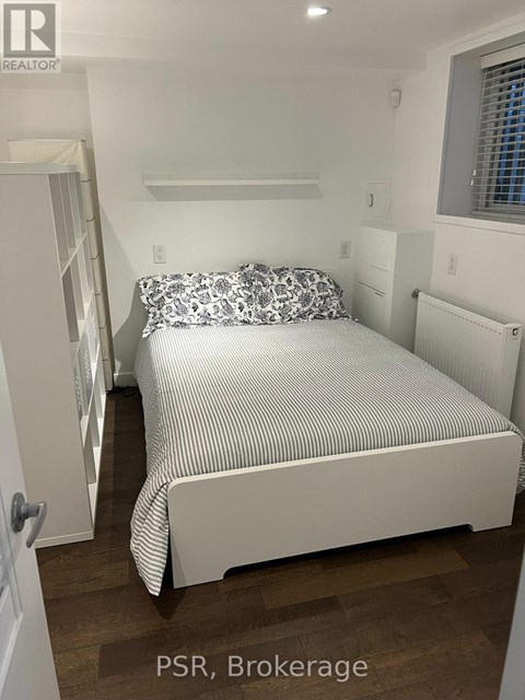 A bedroom with a bed, pillows, and a window.