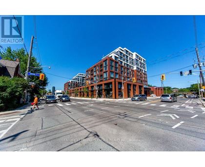 A street view of a city intersection with a large building in the background.