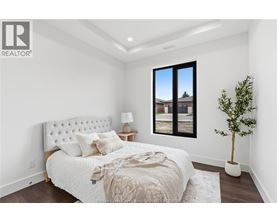 A bedroom with a large bed and a window overlooking a house.
