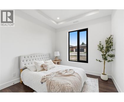 A bedroom with a large bed and a window overlooking a house.