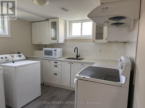 A white kitchen with a washing machine and a microwave.