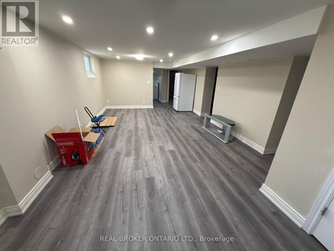 A room with grey flooring and white walls is shown with a Real Broker Ontario Ltd. logo.