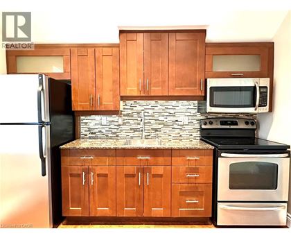 A kitchen with wooden cabinets and a stone backsplash.