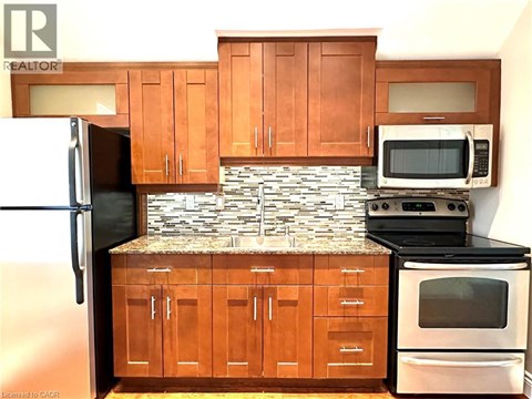A kitchen with wooden cabinets and a stone backsplash.