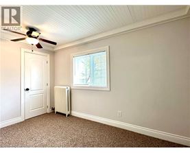 A room with a ceiling fan and a window with blinds.