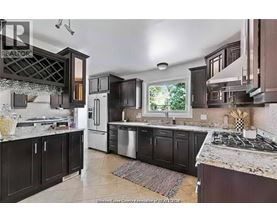 A kitchen with dark brown cabinets and a marble countertop.