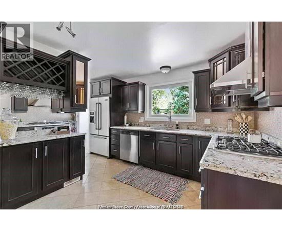 A kitchen with dark brown cabinets and a marble countertop.