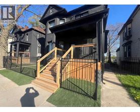 A black house with a wooden staircase leading to the front door.