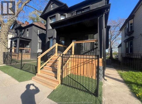 A black house with a wooden staircase leading to the front door.