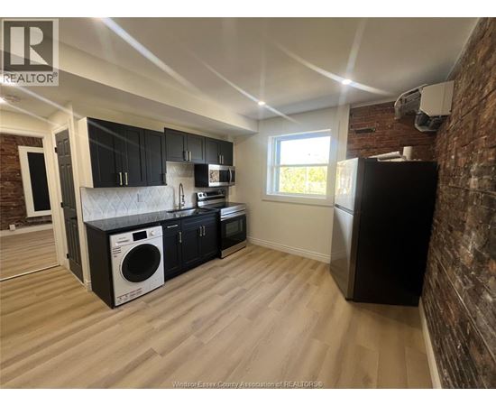 A kitchen with black cabinets and a brick wall.
