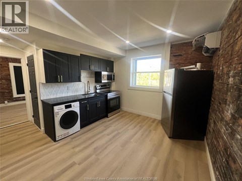 A kitchen with black cabinets and a brick wall.