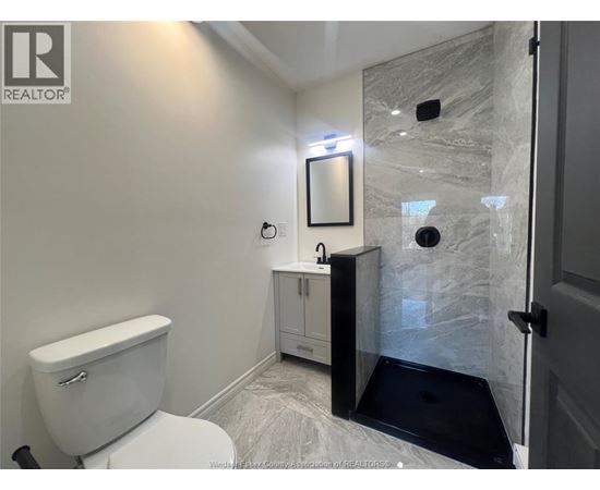 A white toilet is in a bathroom with a marble shower.