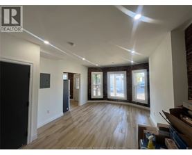 A spacious room with wooden floors and a large window.