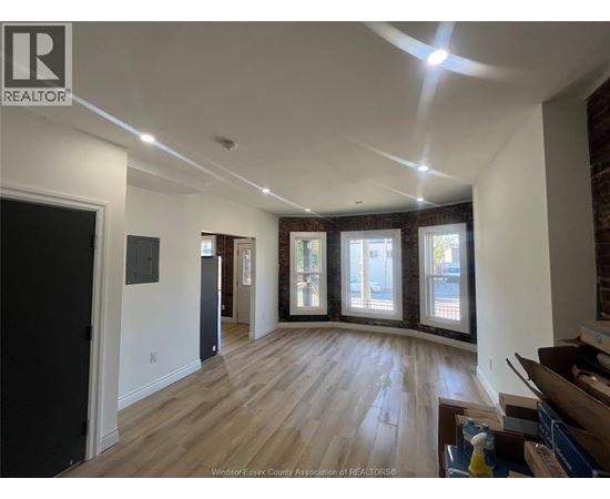 A spacious room with wooden floors and a large window.
