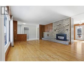 A spacious living room with a stone fireplace and wooden floors.