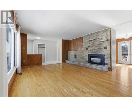 A spacious living room with a stone fireplace and wooden floors.