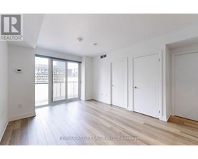 A spacious room with wooden flooring and white walls.
