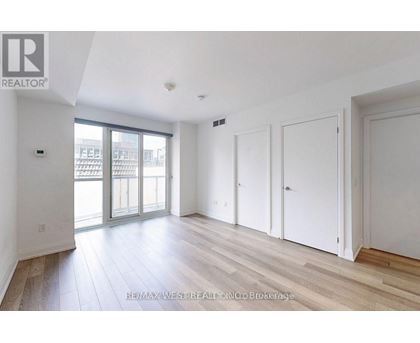 A spacious room with wooden flooring and white walls.