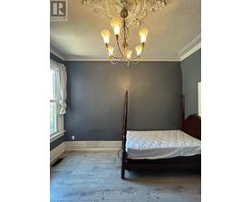 A bedroom with a four poster bed and a chandelier.