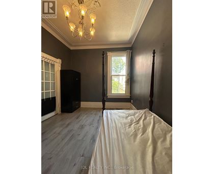 A bedroom with a bed, window, and chandelier.