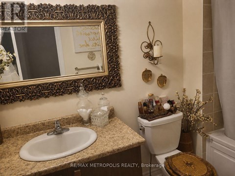 A bathroom with a sink, toilet, and mirror.