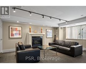 A living room with a black leather couch, a black ottoman, and a glass coffee table.