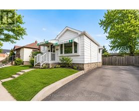 A white house with a green awning is for sale.