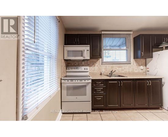 A kitchen with a white microwave and stove top oven.