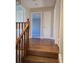 A hallway with a wooden staircase leading to a landing with a blue door.