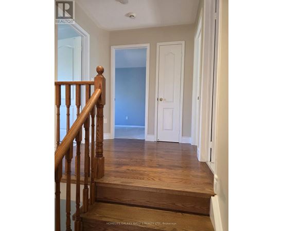 A hallway with a wooden staircase leading to a landing with a blue door.