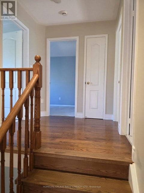 A hallway with a wooden staircase leading to a landing with a blue door.