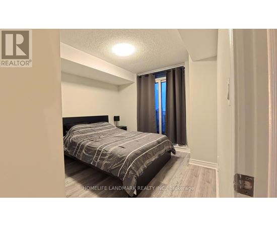 A bedroom with a bed, nightstand, and window with curtains.