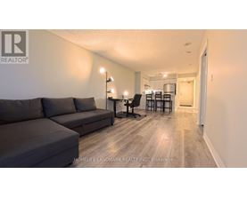 A living room with a grey couch and a wooden floor.