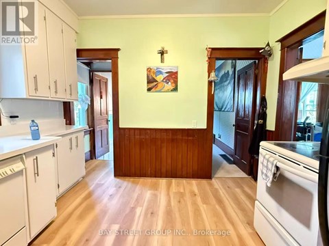 A kitchen with white cabinets and a wooden wall.