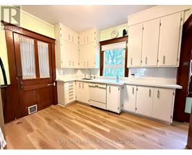 A kitchen with white cabinets and a wooden floor.
