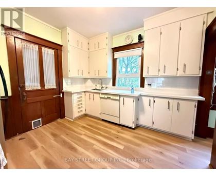 A kitchen with white cabinets and a wooden floor.