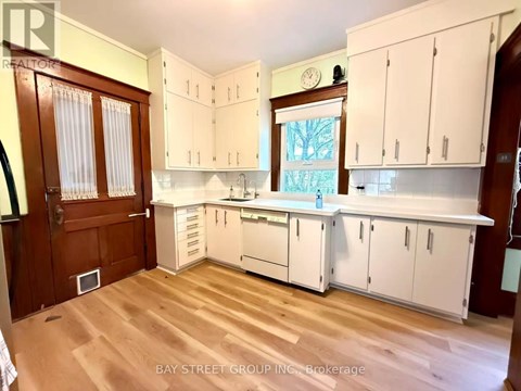 A kitchen with white cabinets and a wooden floor.