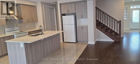 A kitchen with a refrigerator, sink, and stove.