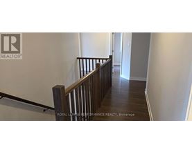 A hallway with a wooden railing and a white wall.