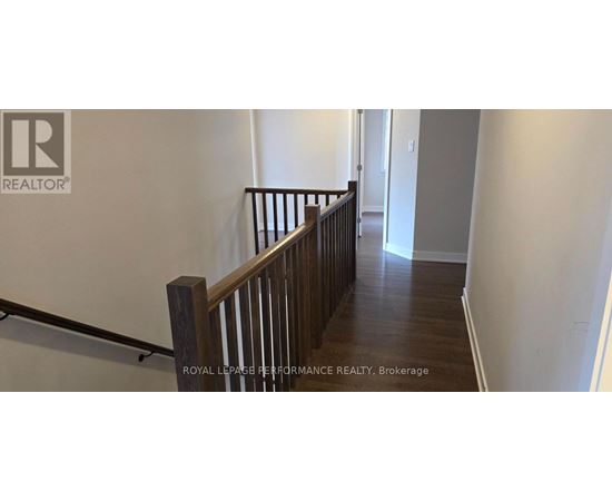 A hallway with a wooden railing and a white wall.