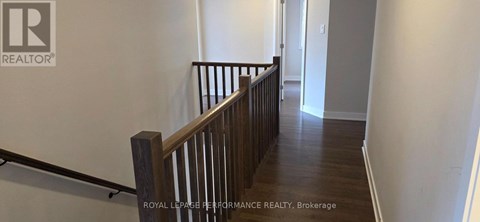 A hallway with a wooden railing and a white wall.