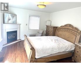 A bedroom with a large bed, a fireplace, and a dresser.