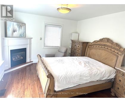 A bedroom with a large bed, a fireplace, and a dresser.