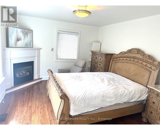 A bedroom with a large bed, a fireplace, and a dresser.