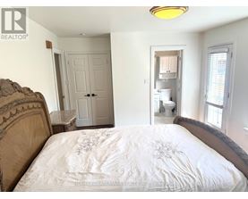 A bedroom with a bed, a toilet, and a sink in the background.