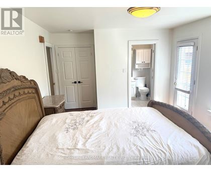 A bedroom with a bed, a toilet, and a sink in the background.